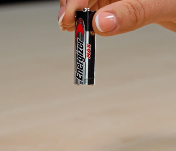 Person lässt eine AA Batterie von 10 cm fallen. 