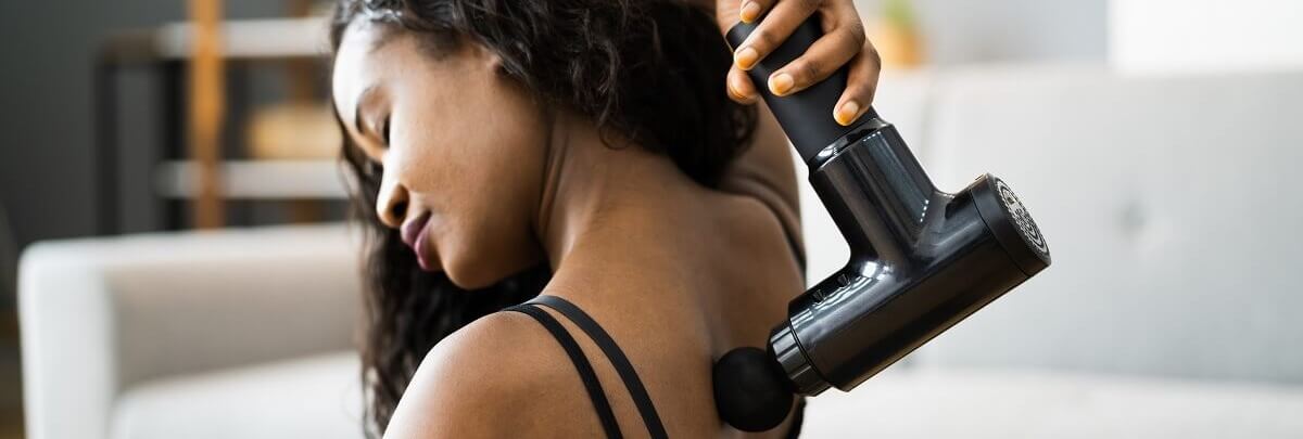 Frau massiert Rücken mit Beurer Massagepistole