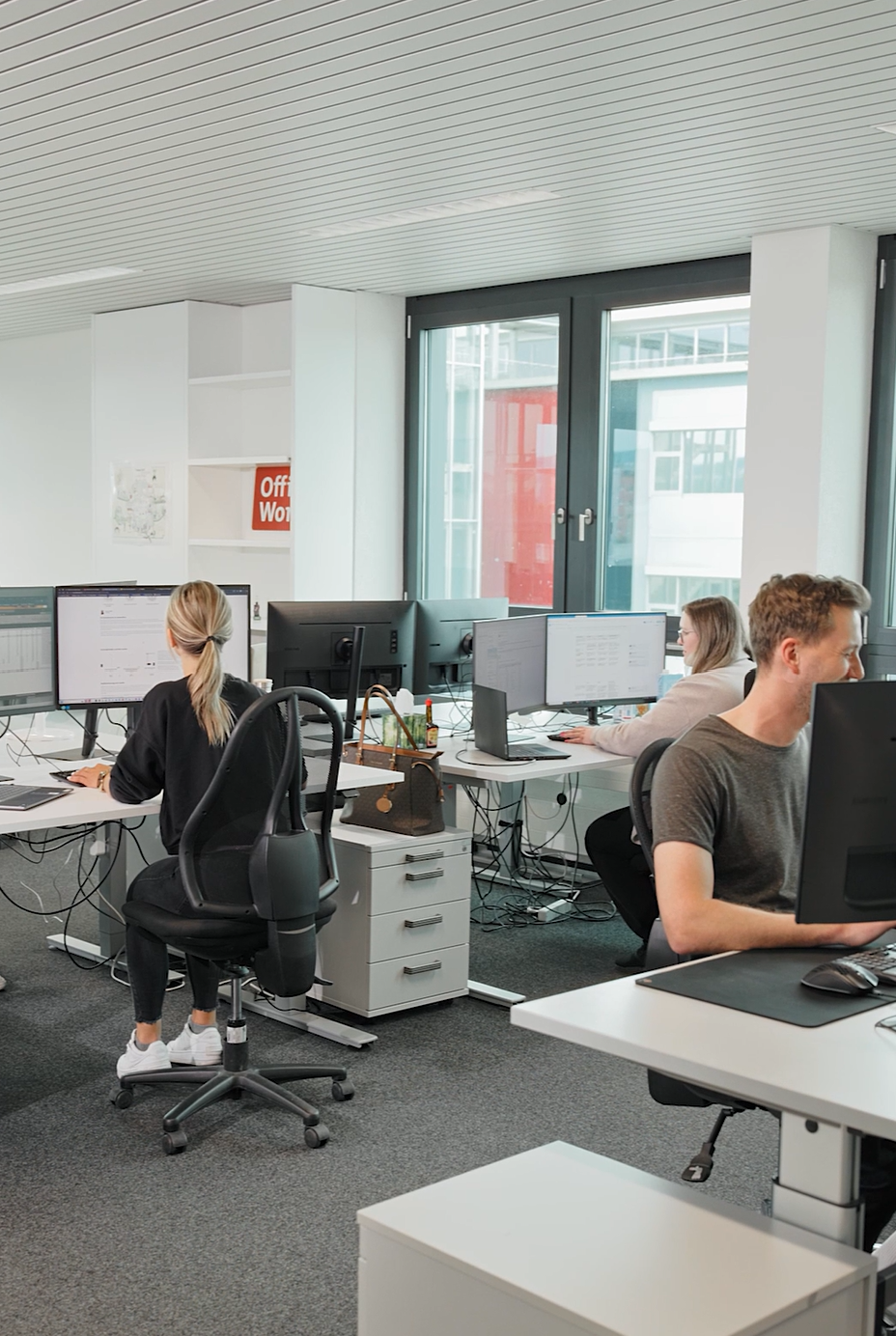 Grossraumbüro mit Mitarbeitern an ihren Arbeitsplätzen