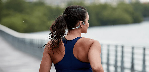 Frau joggt mit Shokz OpenRun Kopfhörern