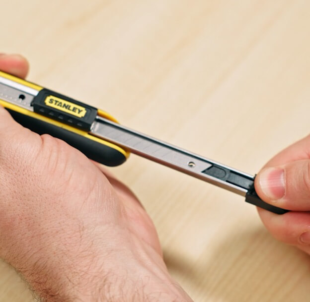 Person zieht Magazin mit Ersatzklingen aus Cutter-Gehäuse