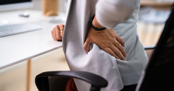 Eine Person beklagt aufgrund schlechter Ergonomie Rückenschmerzen
