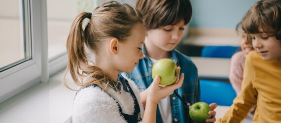 Schulkinder essen gemeinsam grüne Äpfel