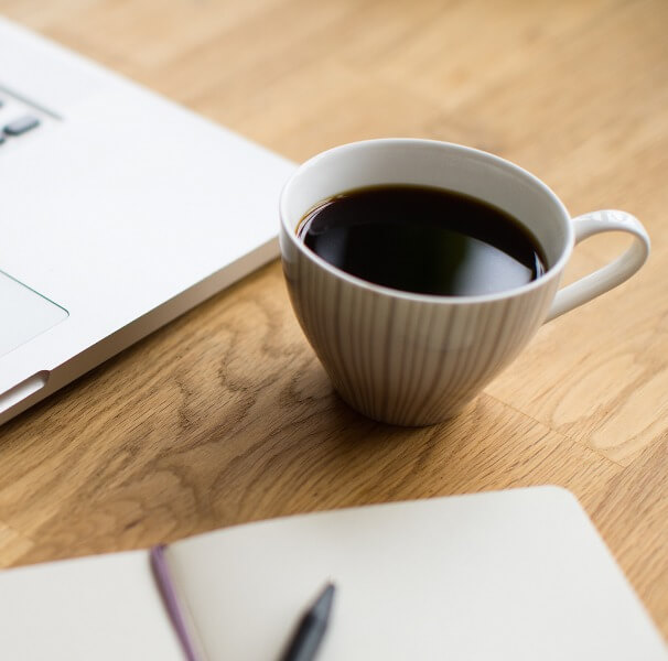Eine Tasse Kaffee steht neben einem Laptop