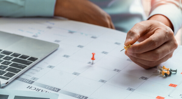 Mann steckt Pin in Businesskalender