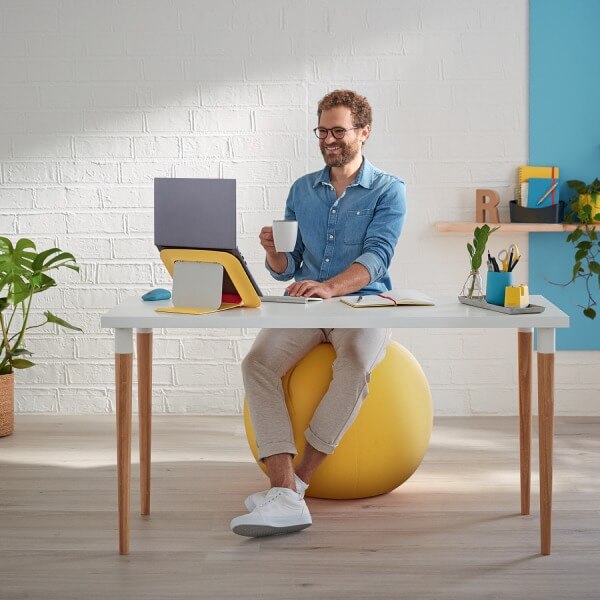 Mann sitzt auf Leitz Ergo Cosy gelbem Sitzball