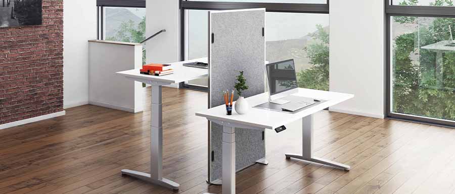 Büromöbelprogramm Tarys mit 2 unterschiedlich hoch eingestellten höhenverstellbaren Tischen, die mit einer Akustikwand frontal getrennt sind.
