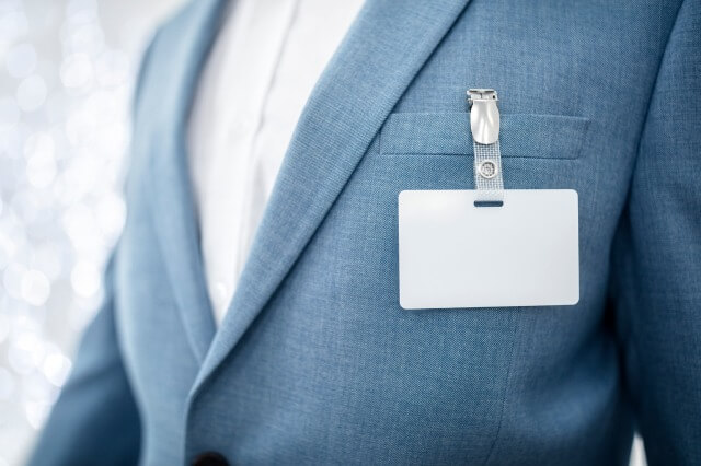 Eine Person hat ein Namensschild mit Clip an ihrem Anzug befestigt