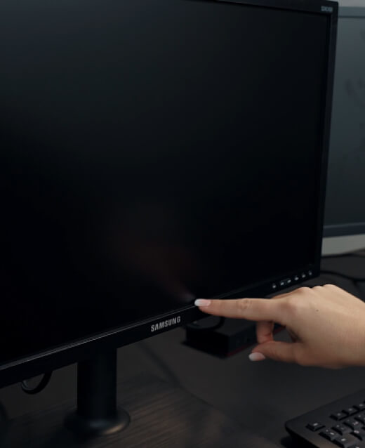 Person zeigt mit dem Finger auf die Randspalte eines Monitors