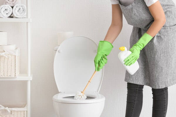 Person reinigt Toilette mit WC-Reiniger