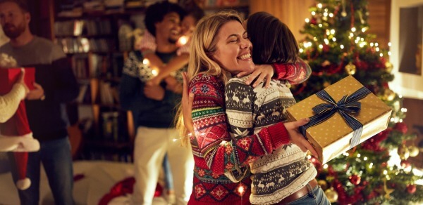 Zwei Frauen umarmen sich vor einem Weihnachtsbaum