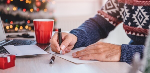Mann schreibt Weihnachtskarte von Hand