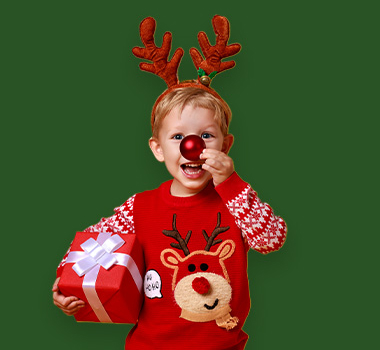 Kind mit Rentiergeweih hält Weihnachtsgeschenk und lächelt