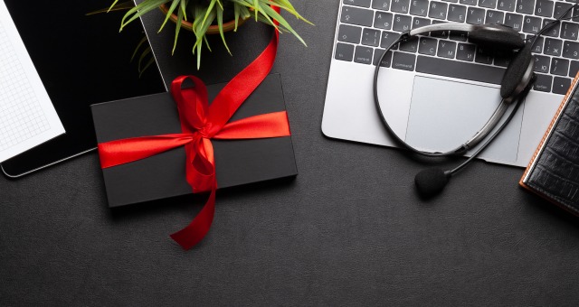 Ein Geschenk für einen Mann liegt neben einem Laptop und einem Headset