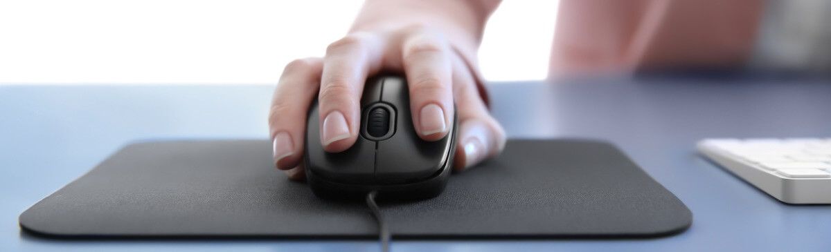 Eine Frau bedient eine Computer-Maus auf einer Mausmatte im Büro