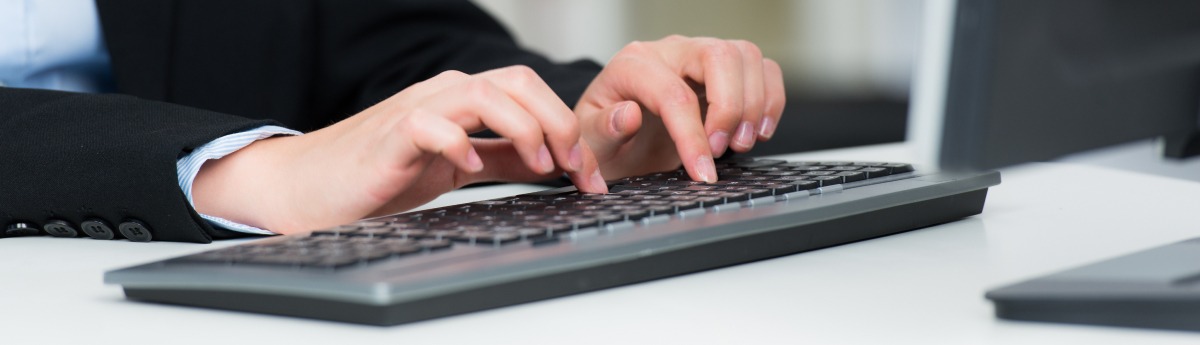 Eine Frau tippt im Büro auf einer PC-Tastatur