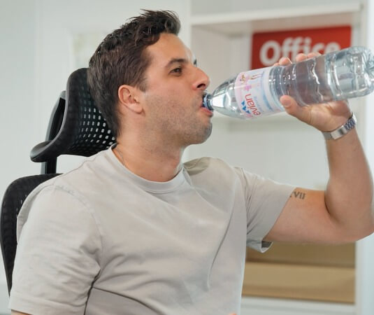 Ein Mann trinkt von einer PET Flasche.