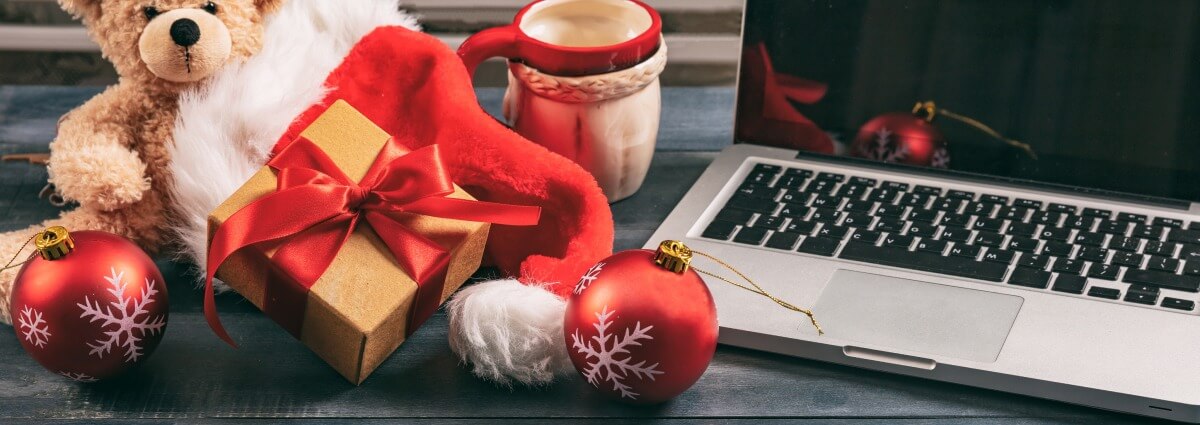 Ein Weihnachtsgeschenk liegt zwischen einem Laptop und Weihnachtsdekoration